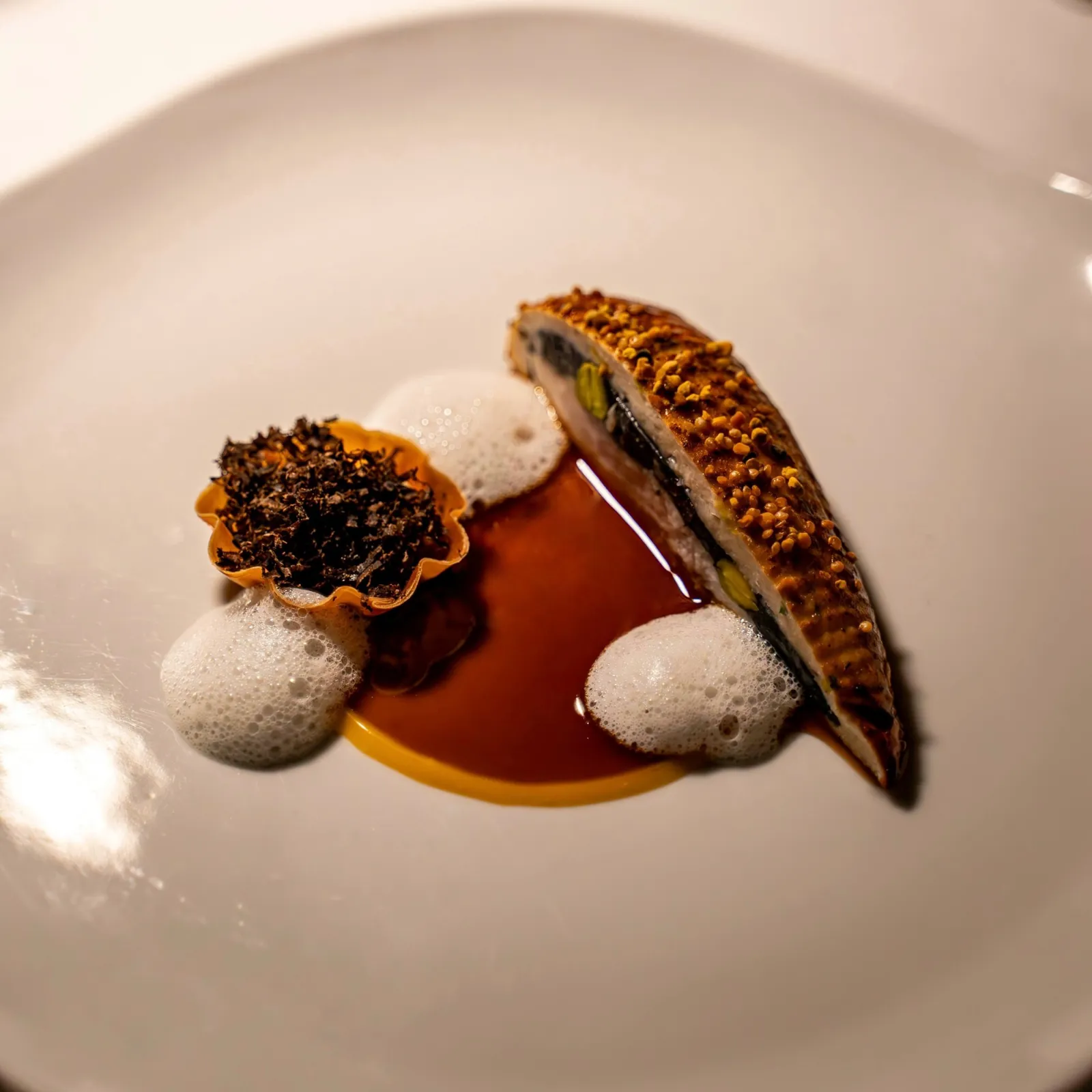 Un plat de Baci : volaille farcie en croûte dorée, jus, émulsion et tartelette à la truffe