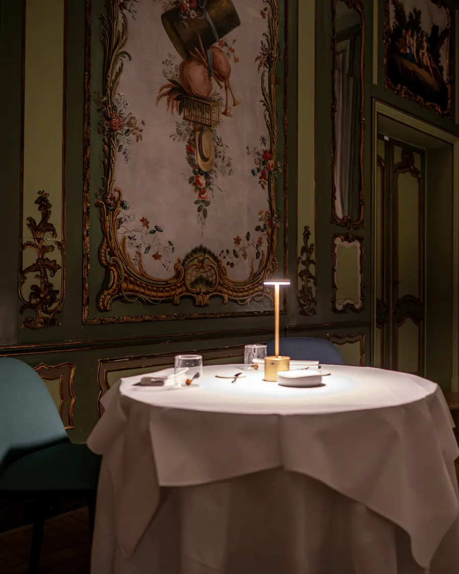 Une table dressée au centre d’un salon aux boiseries peintes, chez Baci