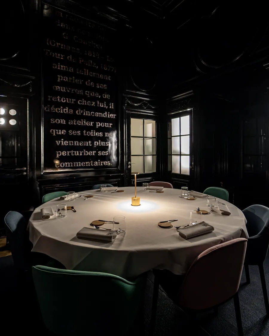 Le Salon Noir : une grande table ronde dressée, murs sombres et texte doré