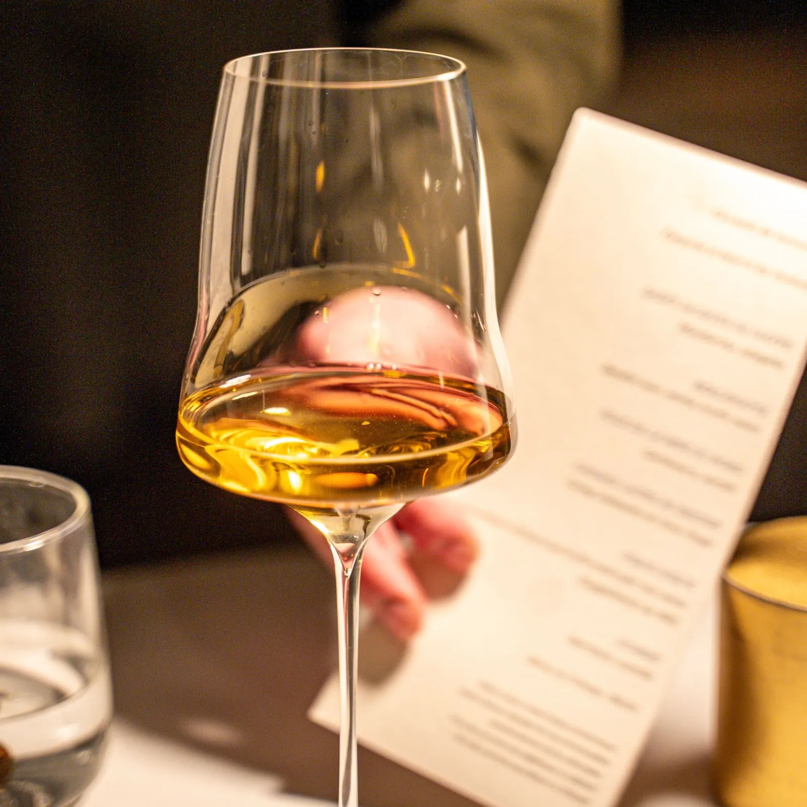 Un verre de vin blanc à table, le menu en arrière-plan